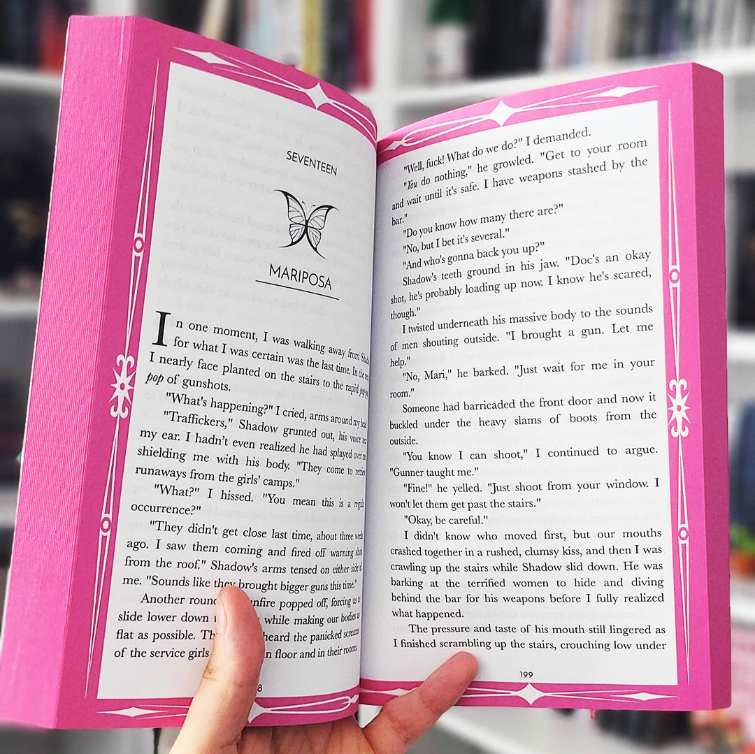 Open book with pink cover held by a hand, blurred background