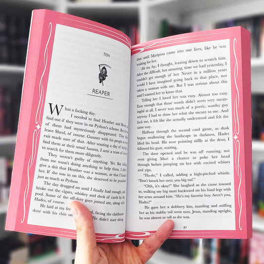 Open book with pink cover held by a hand, blurred background