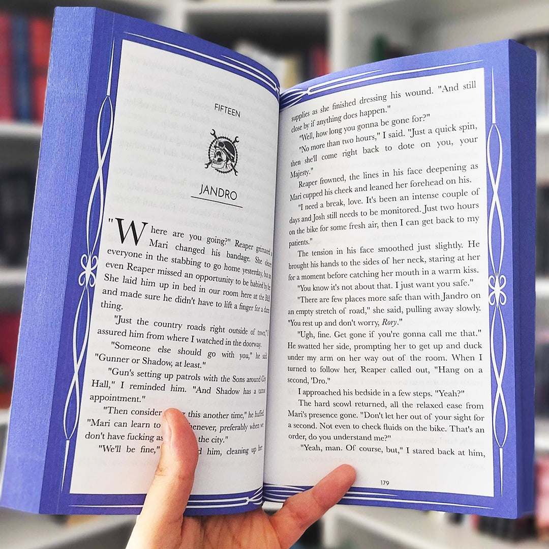Open book with decorative blue cover held by a hand, blurred background