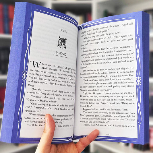 Open book with decorative blue cover held by a hand, blurred background
