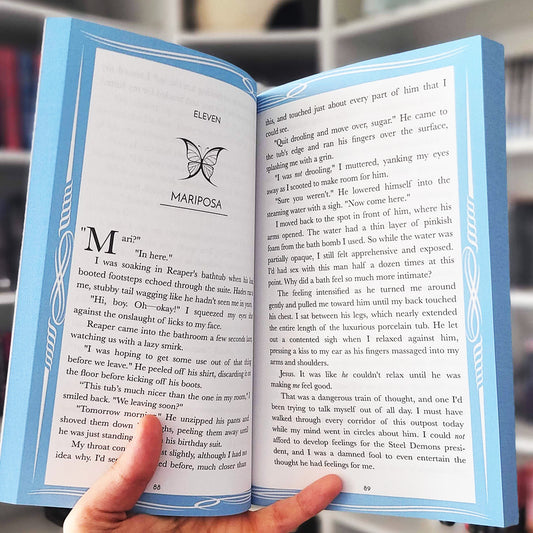 Open book with blue edges held by a hand, featuring text and a butterfly illustration.